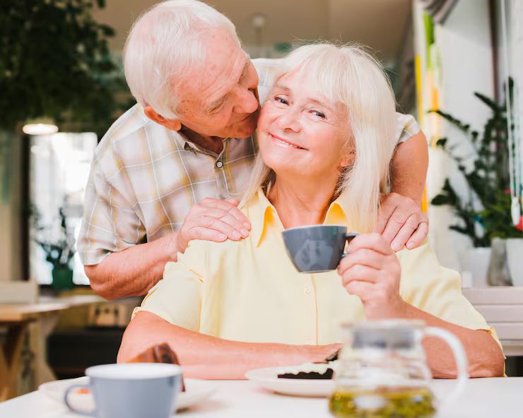 An older couple smiling over tea at home